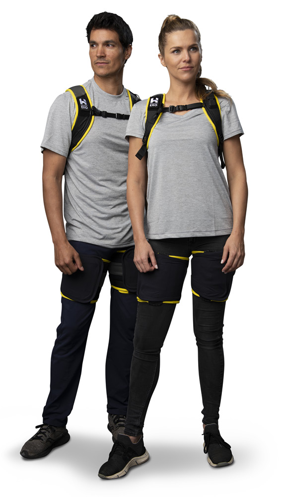 Man model and woman model wearing grey clothes wearing HeroWear Apex exosuit in standing position.